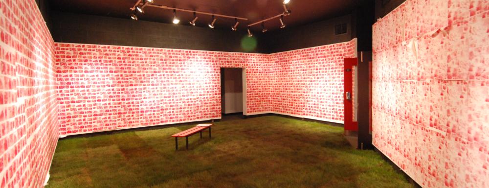 Room with turf on floor, bench in middle and red bricks painted on the walls