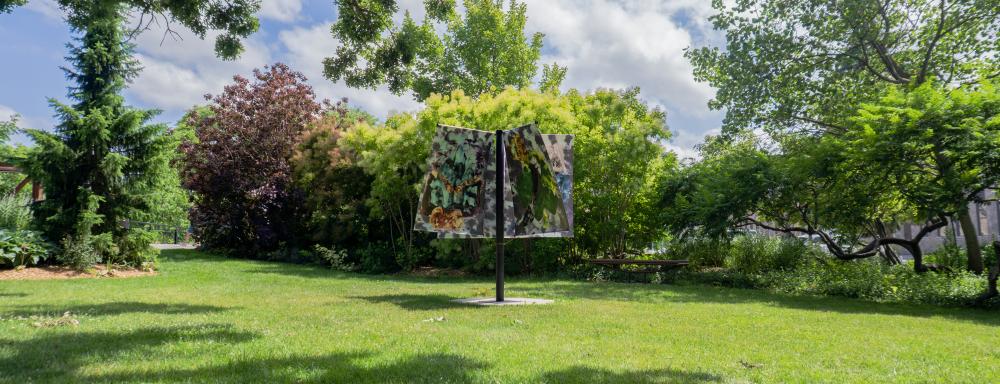 A black pole holds five banners depicting ink drawings of imagined characters